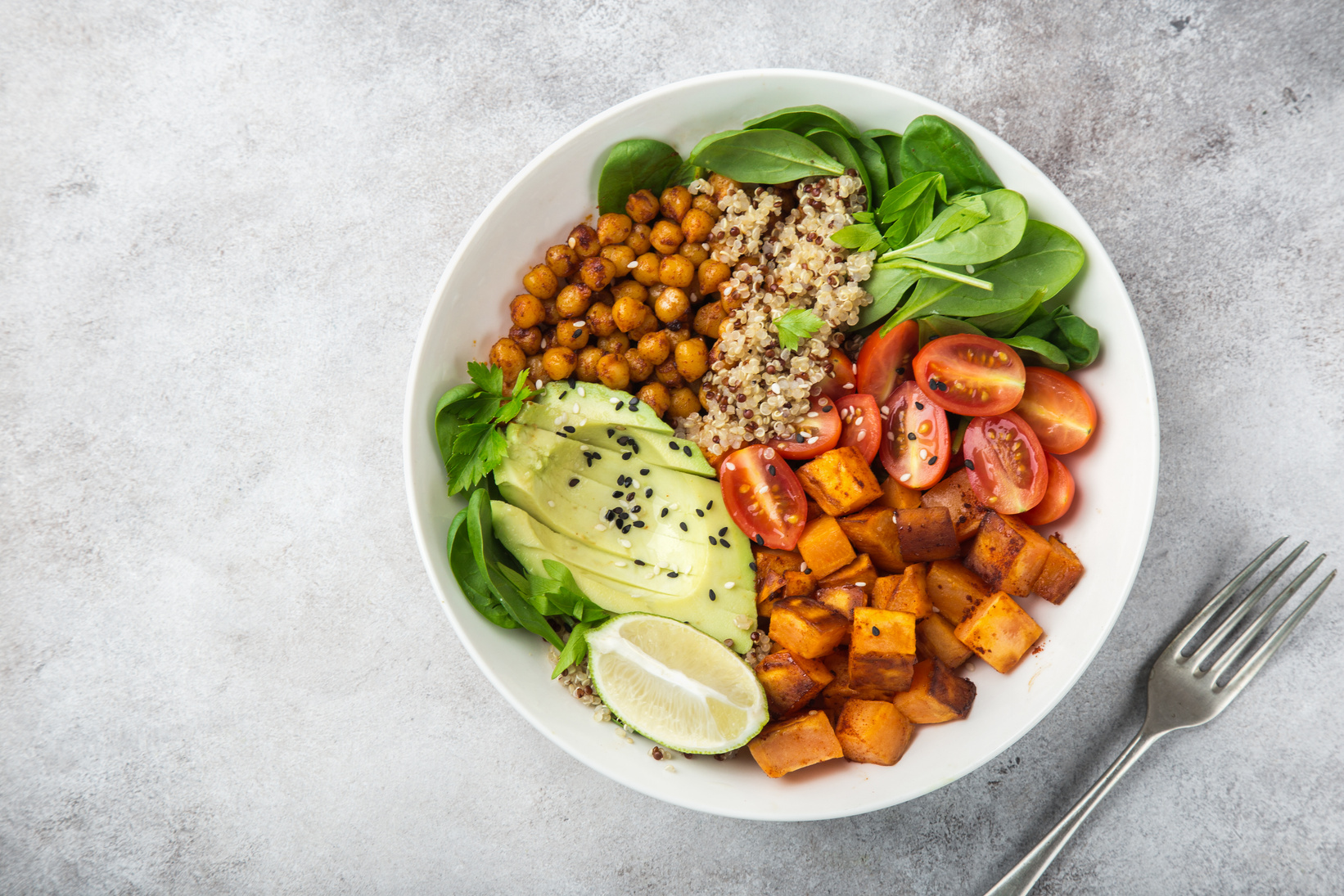 healhty vegan lunch bowl. Avocado, quinoa, sweet potato, tomato, spinach and chickpeas vegetables salad